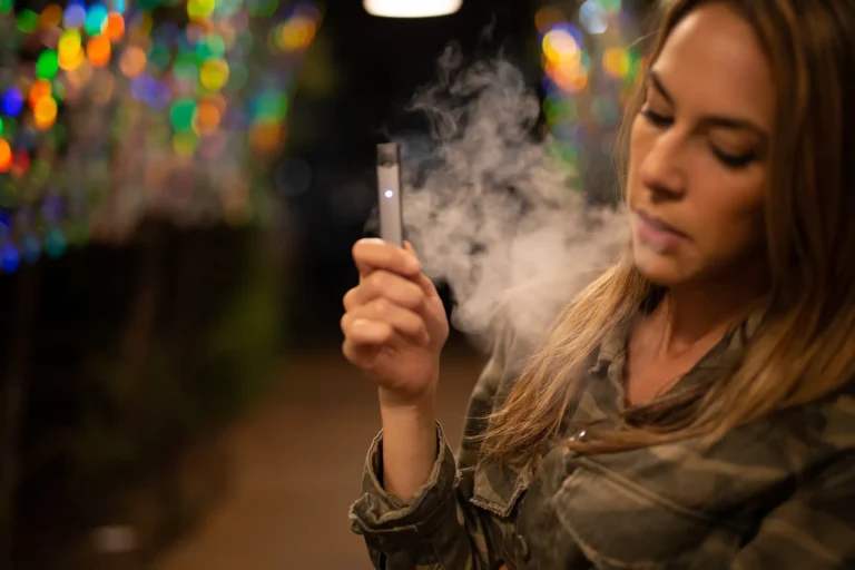 鹽博士煙油夜間戶外抽吸體驗,女性玩家使用小煙主機吞吐濃郁煙霧,展示正品煙油的高效能與純淨霧化效果
